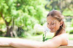 Side view of a woman smelling a flower