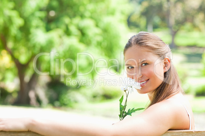 Side view of a smiling woman smelling a flower