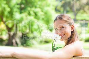 Side view of a smiling woman smelling a flower