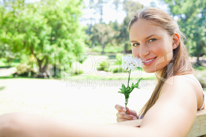 Side view of a smiling woman smelling a flower in the park