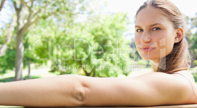 Side view of a woman sitting on a park bench