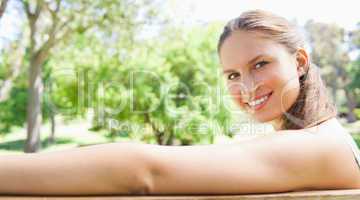 Side view of a smiling woman sitting on a park bench