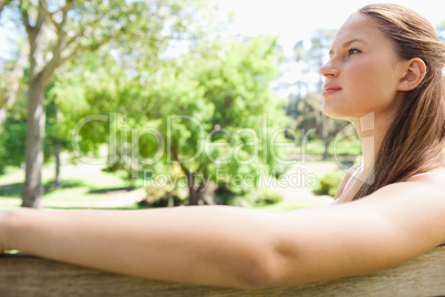 Side view of a woman sitting on a park bench