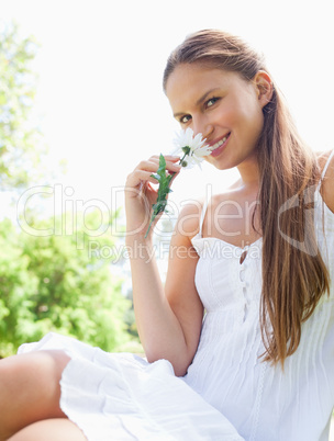 Smiling woman in the park smelling a flower