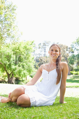 Smiling woman in the park sitting on the lawn