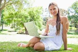 Smiling woman with s laptop on the lawn