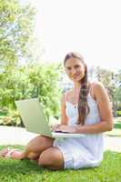 Smiling woman on the lawn with her laptop