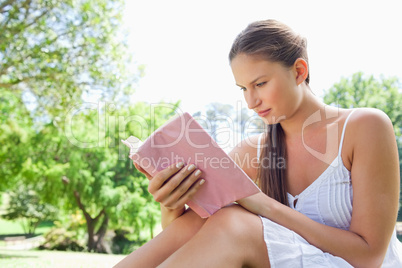Side view of a woman reading a novel in the park