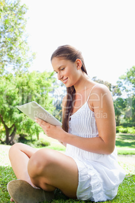 Side view of a smiling woman using a tablet computer in the park