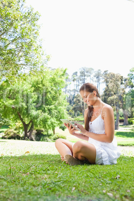 Side view of a smiling woman on the lawn with a tablet computer