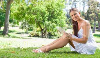 Smiling woman with her tablet on the lawn
