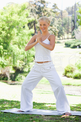 Smiling woman doing yoga exercises in the park