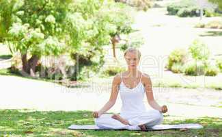 Woman sitting in a yoga position in the park