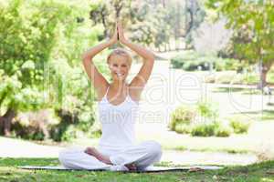 Smiling woman sitting in a yoga position outdoors