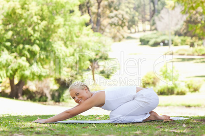 Side view of a woman doing stretches on the lawn