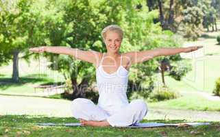 Smiling woman on the lawn doing yoga exercises