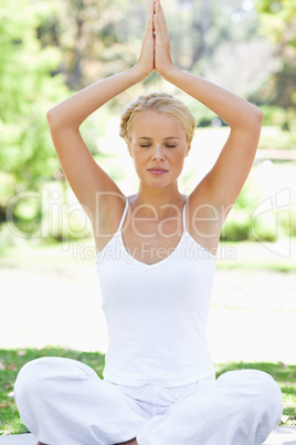 Relaxed woman in a yoga position on the meadow