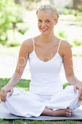 Smiling woman in a yoga position on the grass