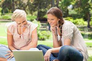 Smiling women in the park with a laptop