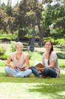 Smiling women with their books sitting in the park