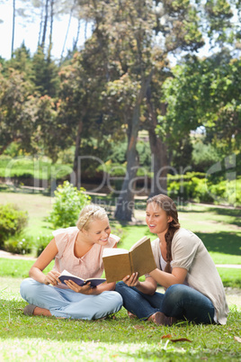Woman showing her friend something in her book