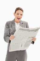 Surprised businesswoman standing reading the newspaper