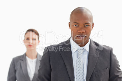 Businessman staring at camera with businesswoman behind him