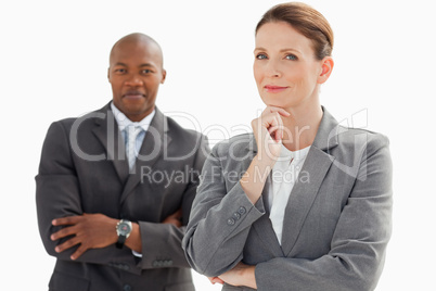 Smiling businessman behind businesswoman rests head on hand