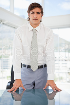 Serious businessman leaning on a table