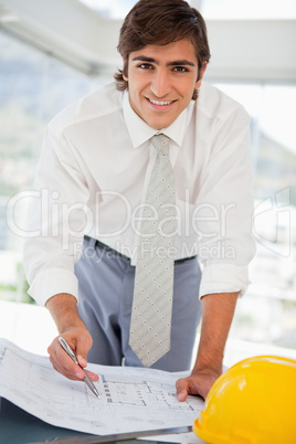 Smiling businessman with blueprints and a hard hat