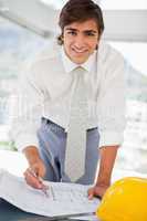 Smiling businessman with blueprints and a hard hat