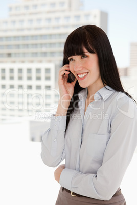 Smiling woman in the office talking on a mobile