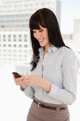 Smiling woman at work sending a text message