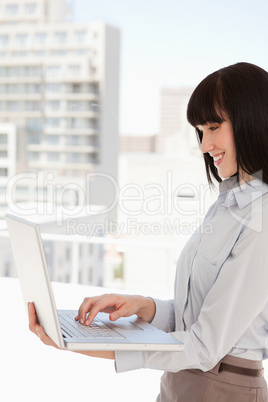 A smiling woman uses her laptop at work