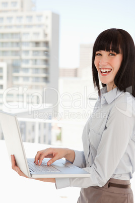 A laughing business woman with a laptop in her hands