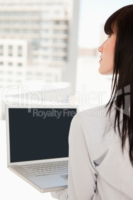 Woman in her office with a laptop in her hand