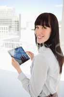 Woman looking into the camera as she holds a tablet pc in her ha