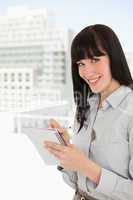 A smiling woman with a note pad and pen looking into the camera