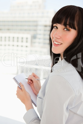 A woman looking back at the camera as she holds a notepad