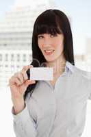 A woman smiling as she holds a business card in front of her