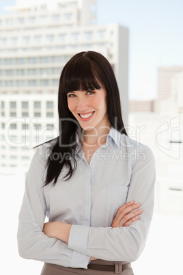 A woman with her arms crossed over and smiling
