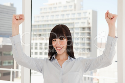 A smiling happy woman with her arms raised just above her head