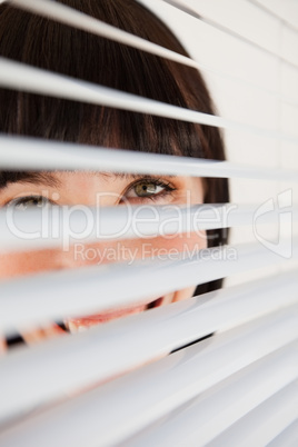 A smiling business woman looking through her blinds