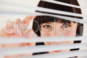 A woman moving open some blinds in front of her