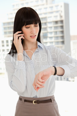 A woman making a quick call as she checks the time