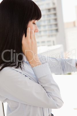 A woman looking at her watch as she calls someone