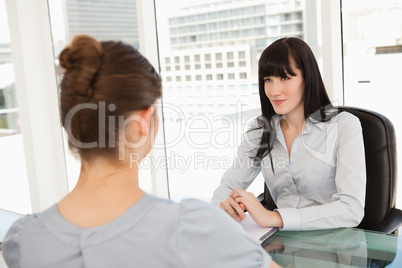 A smiling business woman listens to what the other woman has to