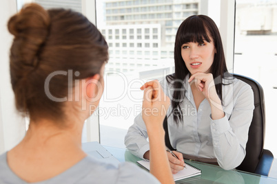 The business woman listens as the candidate employee descibes