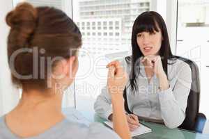 The business woman listens as the candidate employee descibes