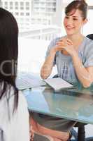 Brunette woman with her hands grouped together smiles